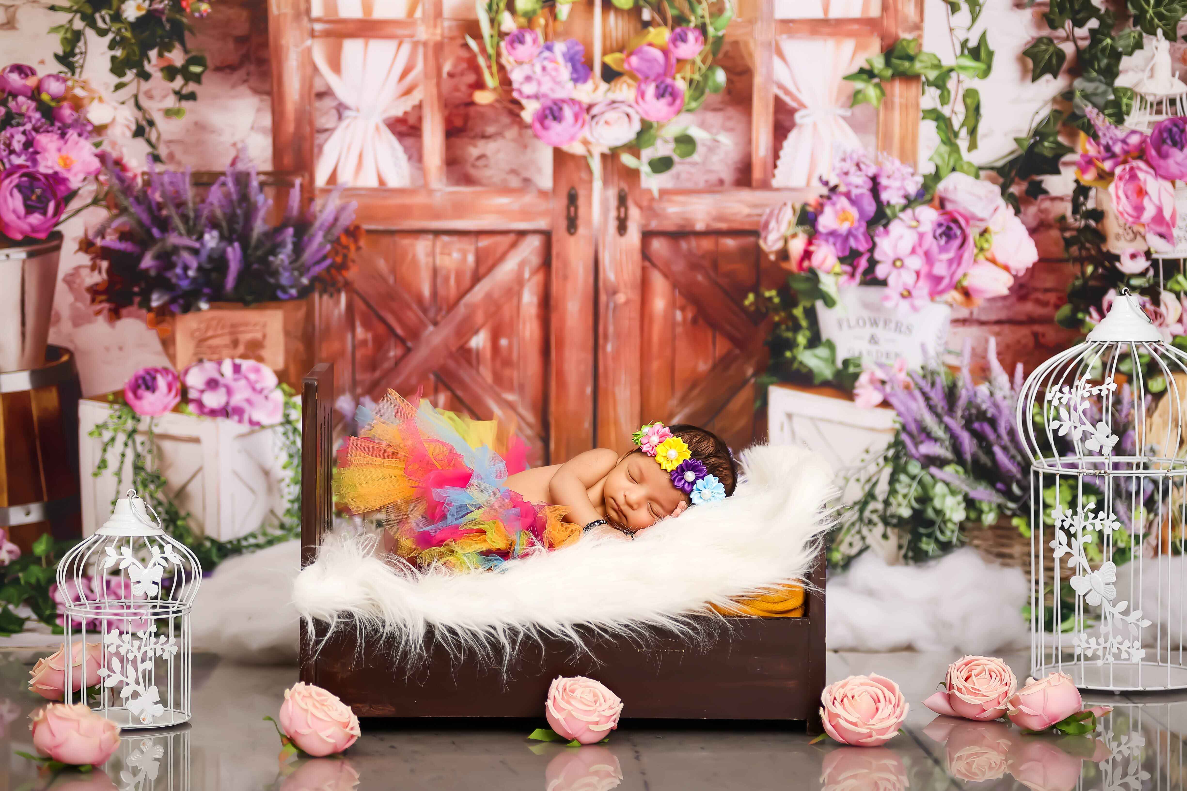 A baby girl in a colorful outfit, peacefully resting on a cozy fur pillow, captured in a floral-themed baby photoshoot.